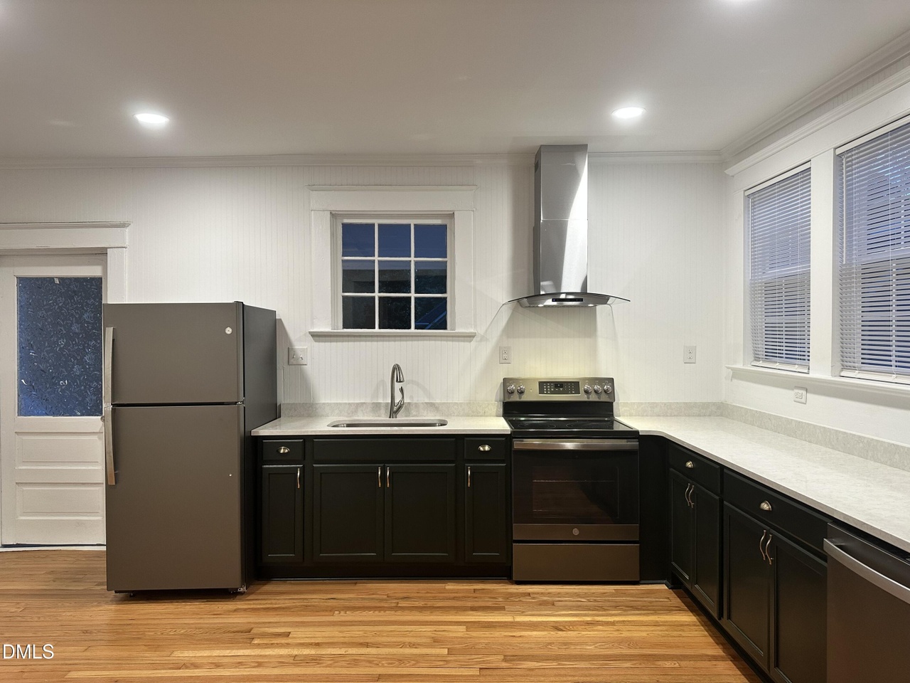 Second renovated kitchen with charcoal cabinets, a stainless range with chimney hood, and a window over the sink